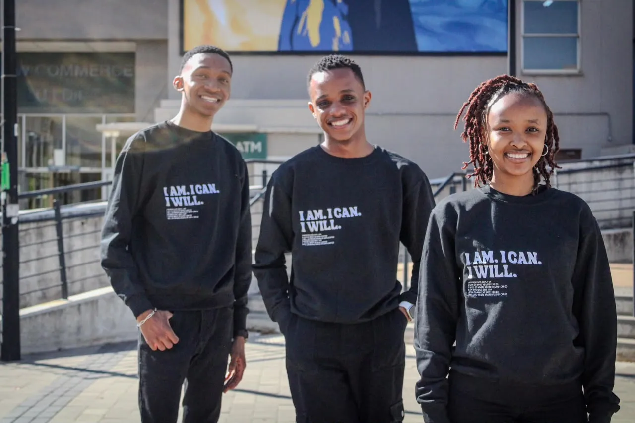 Three students standing together in matching "I Am. I Can. I Will." sweaters